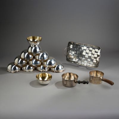 Plusieurs objets en argent sont posés sur une table, à côté d'une bourse en argent
