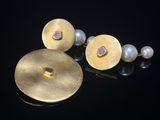 un gros plan sur une paire de boucles d'oreilles ornées de perles, posées sur un fond noir