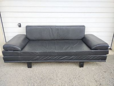 black leather sofa in front of a garage door with a white wall
