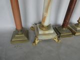 four marble and brass candles are lined up against a white wall