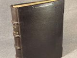 a brown leather book with a gold binding and a black cover