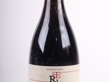 une bouteille de vin rouge avec un bouchon rouge posée sur une surface blanche