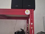 two speakers sitting on a red shelf next to a black bag