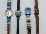 four different watches are lined up on a white surface