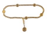 un gros plan sur une ceinture en chaîne dorée ornée d'un pendentif en forme de pièce de monnaie