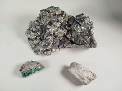 a piece of silver and a rock on a white surface