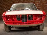 a red and white car parked in front of a brick wall