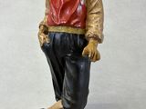 statue of a man wearing a hat and a red vest