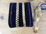 a blue velvet case with gold bracelets and a blue ring