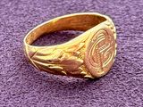 a close up of a gold signet ring on a purple surface