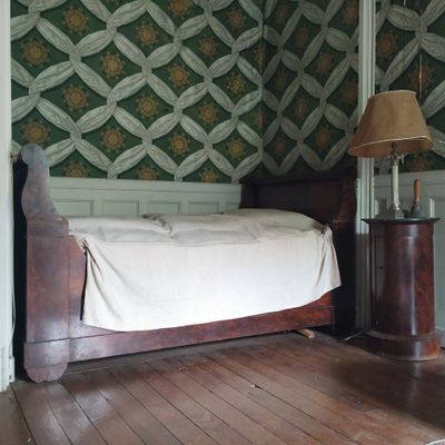 un lit situé dans un coin d'une pièce, avec une lampe