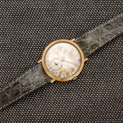 un gros plan d'une montre posée sur une surface noire, avec un cadran blanc