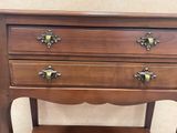 a small wooden table with three drawers on it