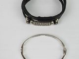 a close up of two bracelets and a ring on a white surface