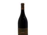 the bottle of red wine is sitting on a white surface