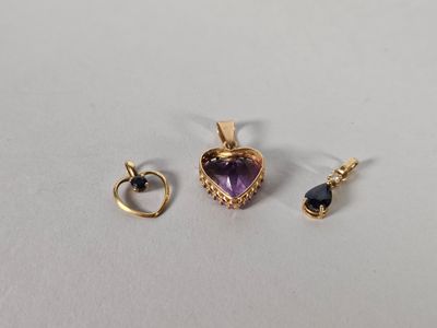 un gros plan sur deux pendentifs en or et en améthyste posés sur une surface blanche