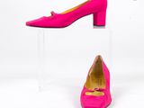 une paire de chaussures roses posée sur un socle en acrylique transparent