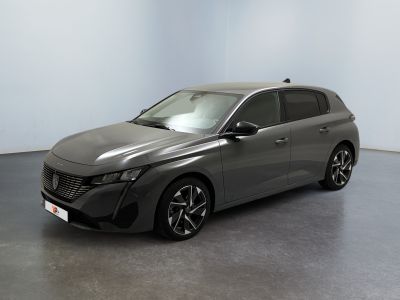La voiture grise est garée dans une grande pièce aux murs blancs.