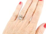 a woman ' s hand with a red manicure holding a diamond ring