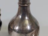a silver bottle and a silver spoon sitting next to each other