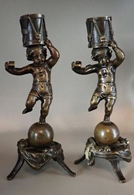 Deux bougeoirs en bronze patiné à décor de putti debout sur …