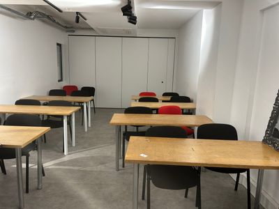 many tables and chairs in a room with a chalk board on the wall