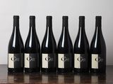 six bouteilles de vin sont posées sur une table devant un mur blanc