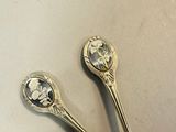 pair of silver spoons sitting on top of a white surface
