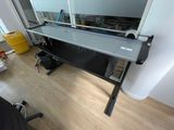 un bureau d'ordinateur avec un plateau en verre, placé dans un coin de la pièce