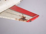 a small red and white airplane with rust on the wing