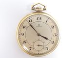 une montre de poche en or sur une surface blanche