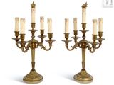 une paire de chandeliers anciens en laiton, chacun orné d'une bougie