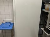 a small white refrigerator in a kitchen with a blue tray on the floor