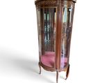 a glass display cabinet with a pink cushion on the bottom