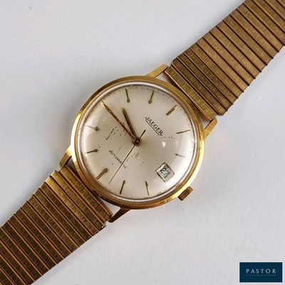 une montre-bracelet en or avec un cadran blanc sur une surface blanche
