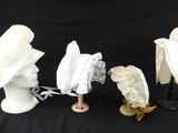 trois chapeaux blancs et un porte-chapeaux sur fond noir