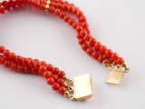 a close up of a red beaded necklace with a gold clasp