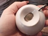 a person holding a small white cup with a finger print on it