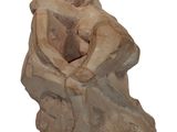statue of a woman sitting on a rock with her hands on her knees