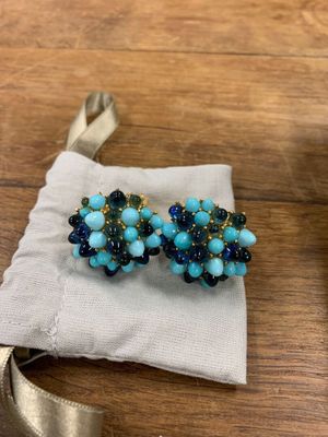 une paire de boucles d'oreilles bleues et vertes posées sur un tissu blanc