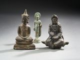 trois figurines en bronze représentant des bouddhas assis sur une surface blanche