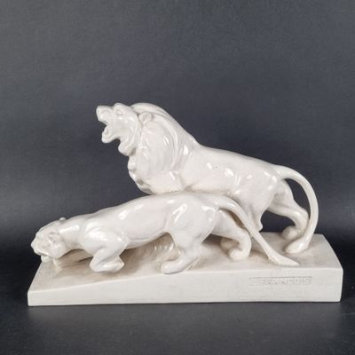 deux figurines de lions posées sur un socle en marbre avec un fond noir