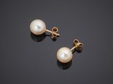 a pair of pearl earrings on a black surface