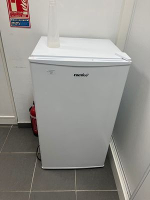 a small white refrigerator in the corner of a room