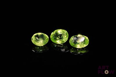 three green gems on a black surface with a black background