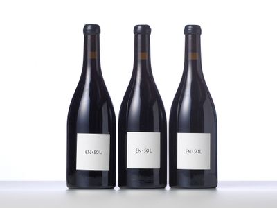 three bottles of wine are lined up on a table