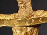 gold statue of a man holding a sword and a shield