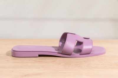 purple sandals on a wooden table with a white wall in the background