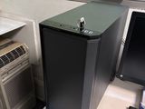 un petit ordinateur noir posé sur un bureau, à côté d'un écran d'ordinateur
