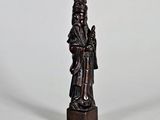 une vieille statue en bois représentant un homme portant un chapeau et une robe